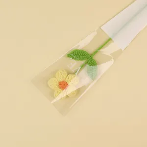 Hand-crocheted yellow puff flower inside a "LOVE" gift packaging sleeve, detail view.