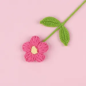 Close-up of a handmade crochet puff flower with pink petals and green leaves.