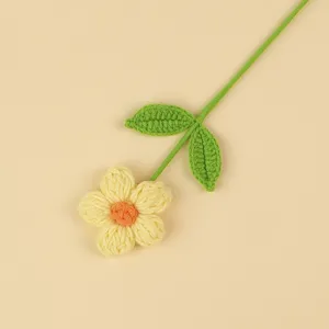 Detailed macro view of a handmade crochet puff flower with yellow petals and green leaves