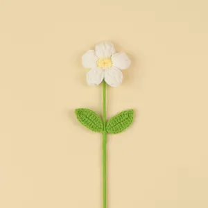 Macro detail of a handmade white crochet puff flower with green leaves and stem