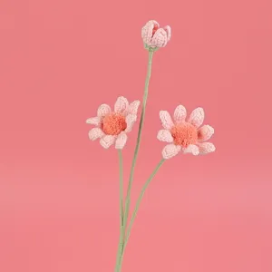 Vista detallada de flores de margarita hechas a mano a ganchillo sobre fondo rosa