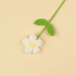 Detailed macro shot of a handmade crochet white puff flower with a green stem and leaves