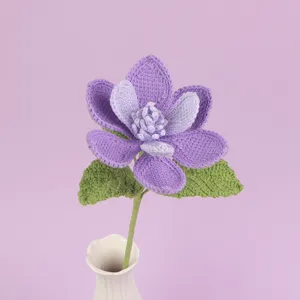 Exquisite detail of a handmade crochet purple magnolia flower set in a white ceramic vase