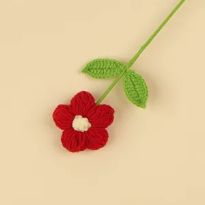Macro view showing the soft texture of a handmade red crochet puff flower with green stem.