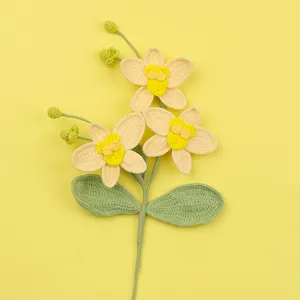 Makro-Detail von handgehäkelten gelben Phalaenopsis-Orchideenblüten mit grünen Blättern