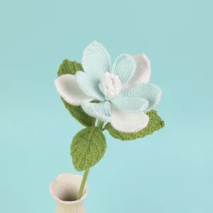Detailed macro view of a handmade crochet Magnolia flower in soft blue and white hues