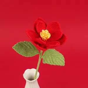 Detail view of a handmade crochet red magnolia flower with yellow stamen in a white vase