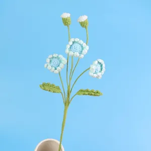 Detailansicht eines handgehäkelten blauen Gänseblümchens mit weicher Garntextur und Blättern