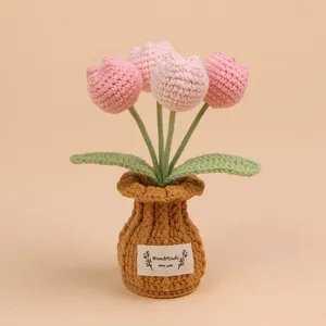 Detailopname van een roze handgehaakte tulp in een bruine geweven pot op beige