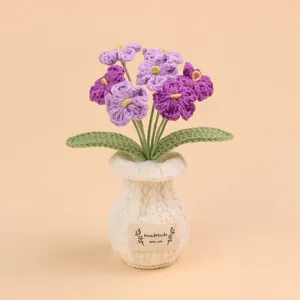 Handgemaakte paarse gehaakte bloemen in een witte geweven vaas met decoratief label.