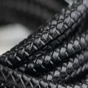 Detalle macro de cordón de cuero vacuno trenzado negro mostrando la textura
