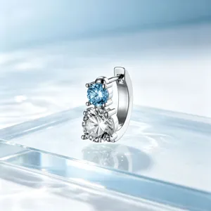 Detailed view of polished titanium steel hoop earring with stacked blue and white crystals.