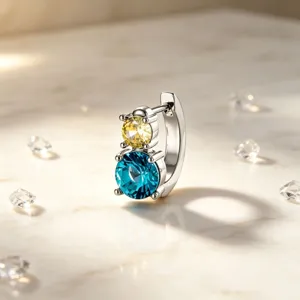 Close-up of silver huggie earring with stacked yellow and blue round-cut crystals