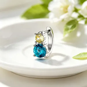 Macro view of titanium steel hoop earring with stacked yellow and teal crystal stones