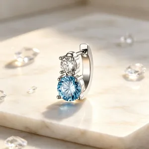Macro view of titanium steel huggie earring with stacked blue and white crystals