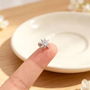 Close-up of a sparkling stainless steel star ear stud on a fingertip for size reference