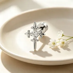 Detailed view of silver punk cross stud earring with clear zircon on a ceramic plate
