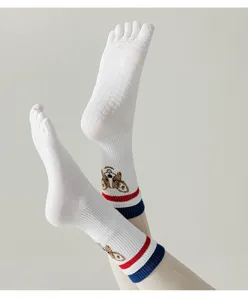 Detalle de calcetines de yoga blancos de cinco dedos con suela de silicona y perrito.