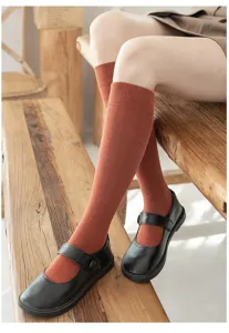 Detailed view of solid color long socks and black leather shoes, warm autumn style scene.