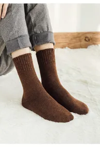 Gedetailleerd opname van dikke bruine winterSokken op pluizig tapijt, warme ribgebreide kleding.