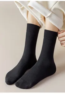 Close-up detail shot of classic solid black mid-tube thermal socks, soft loop knit texture.