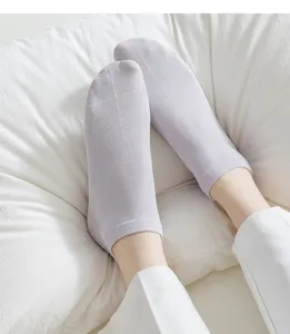 Close-up detail of light purple short ankle socks worn comfortably against a white pillow.