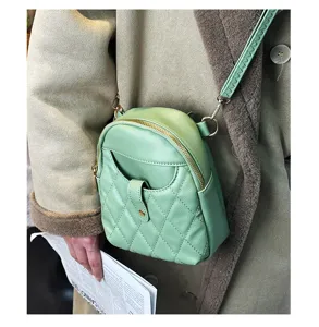 Close-up of mint green quilted soft leather mini crossbody bag on model's coat.