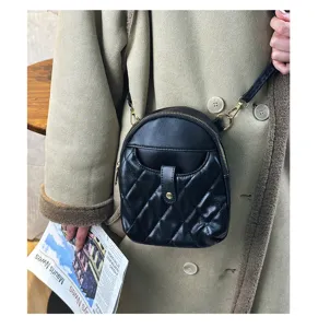 Detailed view of the black quilted mini leather bag worn over a stylish beige winter coat