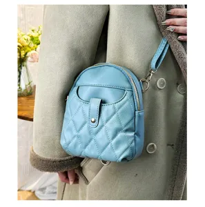 Close-up detail of mini light blue quilted backpack made of soft leather worn on model