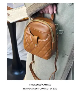 Macro view of a brown quilted mini backpack showing its front pocket and zipper details