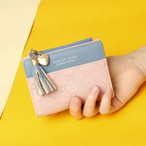 Close-up of small bi-fold wallet held by hand showing texture and tassel detail