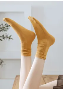 Detail view of yellow rolled cuff socks worn on feet, showing the soft cotton texture.