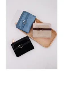 Close-up of three colorful women's patchwork wallets on a wooden tray