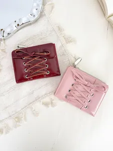Detail view of pink and burgundy short wallets with elegant lace-up bow design on a mat