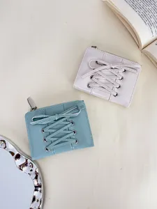 Two chic pastel lace-up bow wallets in blue and cream on a minimal minimalist desk