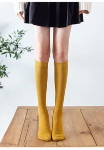 Detailansicht gelber Strick Kniestrümpfe vom Model getragen auf Holztisch, weich.