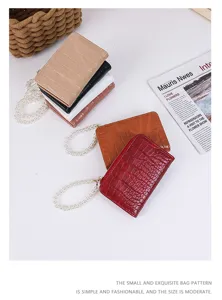 Close-up of small crocodile pattern wallets in various colors with pearl chain straps.