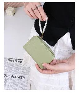 Close-up of green litchi grain coin purse featuring an elegant pearl wrist strap handle