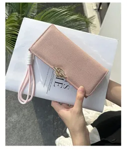 Détail d'un élégant portefeuille long en similicuir rose avec fermoir en métal doré et dragonne