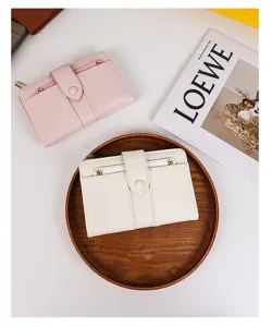 Carteras plegables de cuero PU blanco y rosa presentadas en una bandeja de madera rústica