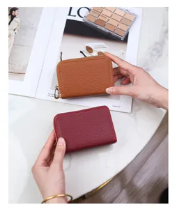 Macro view of brown and burgundy litchi grain accordion card wallets held in hands