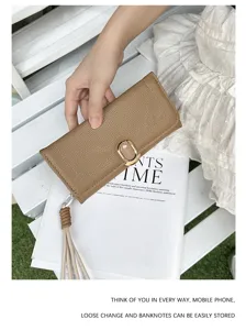 Close-up detail of a brown pebble-grain leather long wallet with an elegant tassel