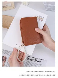 Detailed view of brown lychee grain leather wallet featuring an elegant pearl wrist strap