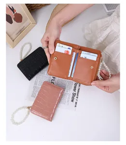 Detail of crocodile pattern women's bi-fold wallet with pearl wristlet and card slots.
