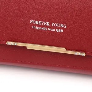 Close-up of red leather texture and gold metal bar detail on a luxury women's wallet bag