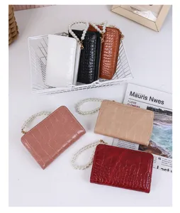 Detail view of colorful crocodile pattern bifold wallets with elegant pearl chains