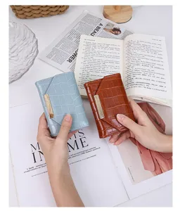 Vue détaillée de portefeuilles courts en similicuir croco tenus sur des magazines