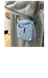 Light blue quilted mini backpack made of soft faux leather worn over a beige coat.