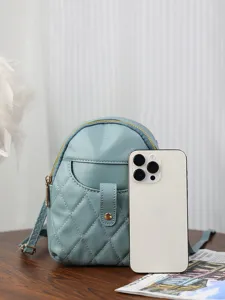 Elegant light blue quilted mini backpack in soft leather shown next to a smartphone.