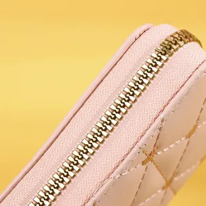 Detailed close-up view of a high-quality golden metal zipper on a pink quilted wallet